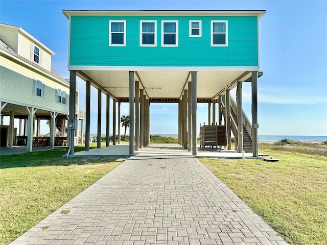 view of community with a carport, stairs, and a lawn
