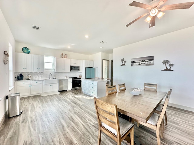 dining area featuring visible vents, light wood-style flooring, baseboards, and ceiling fan