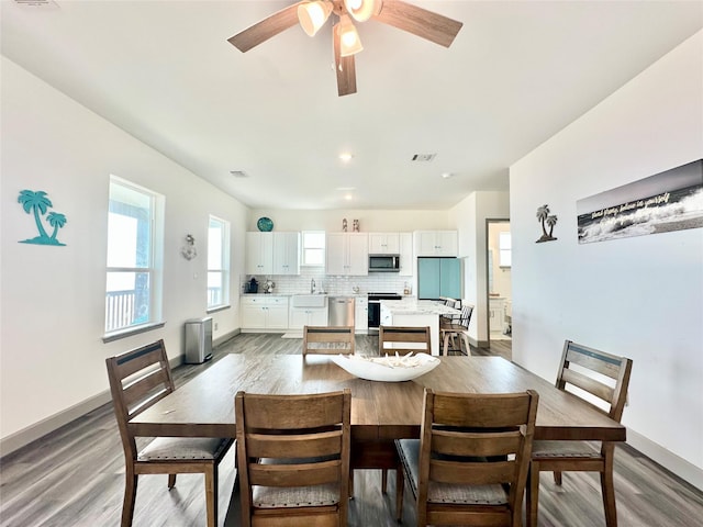 dining room featuring light wood-style flooring, a ceiling fan, visible vents, and baseboards