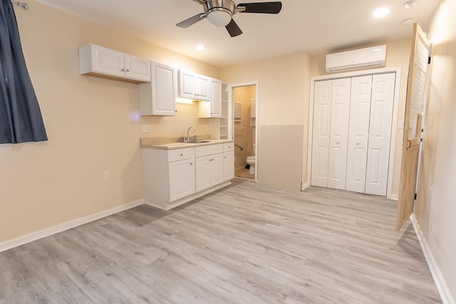 1922 Tabor St, Houston, TX 77009 - kitchen featuring an AC wall unit, white cabinetry, a sink, a ceiling fan, and light wood-style flooring