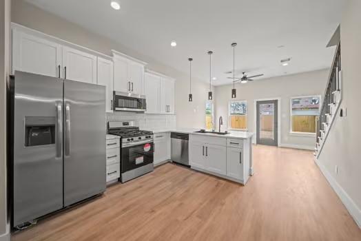 8120 Colonial Ln, Houston, TX 77051 - kitchen with light wood-type flooring, a ceiling fan, a sink, appliances with stainless steel finishes, and a peninsula