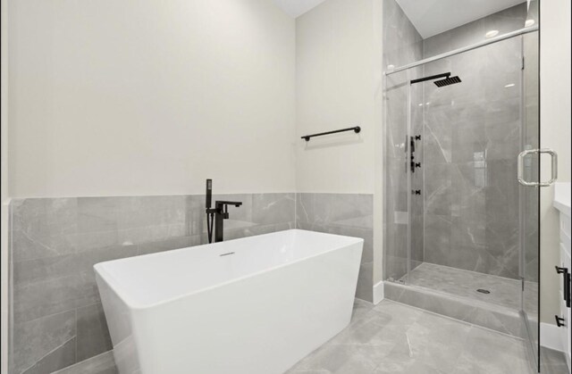 bathroom featuring a freestanding bath, tile walls, a stall shower, and wainscoting