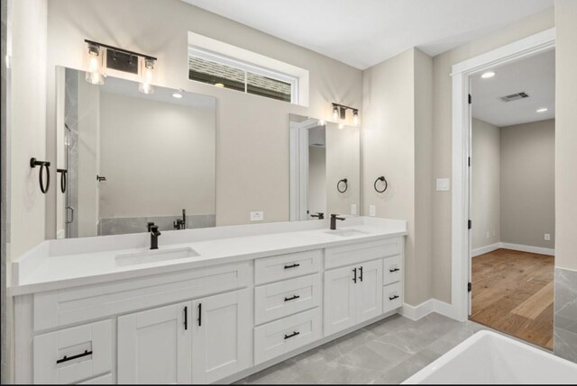 bathroom featuring double vanity, visible vents, baseboards, and a sink