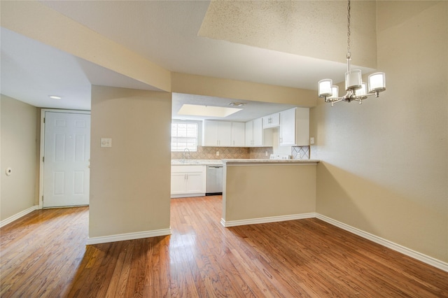 kitchen with white cabinetry, stainless steel dishwasher, a sink, baseboards, and light wood-type flooring