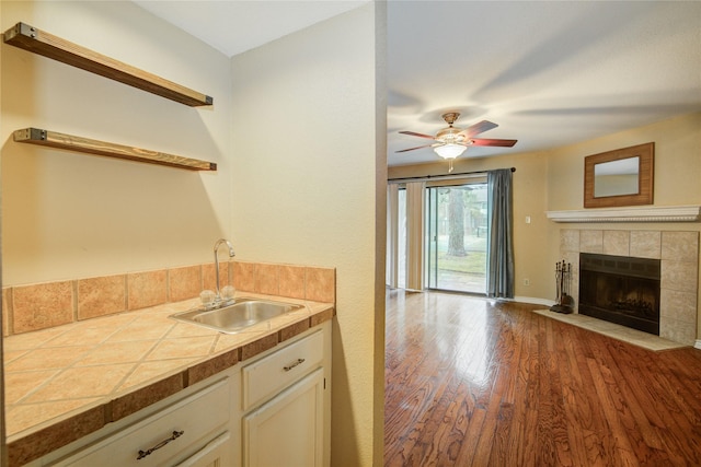 kitchen with wood finished floors, open shelves, white cabinets, a sink, and tile countertops