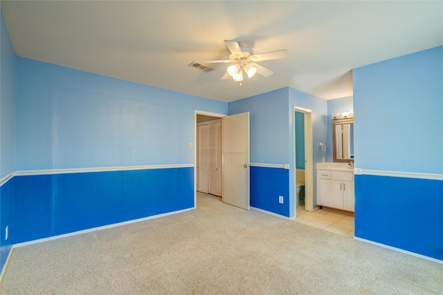 unfurnished bedroom with carpet flooring, visible vents, baseboards, a ceiling fan, and tile patterned flooring