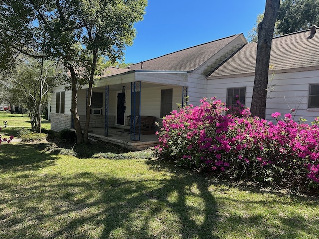 exterior space with roof with shingles, covered porch, and a front lawn