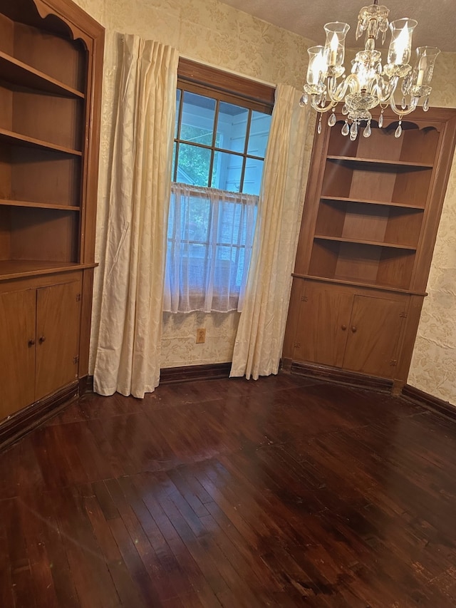 unfurnished dining area featuring baseboards, dark wood-style flooring, and a notable chandelier