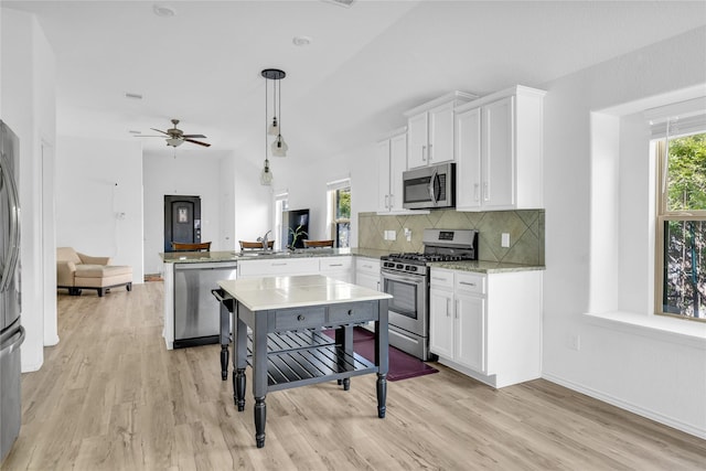 18406 Hilltop Climb Dr, Hockley, TX 77447 - kitchen with appliances with stainless steel finishes, white cabinets, light wood finished floors, and a peninsula