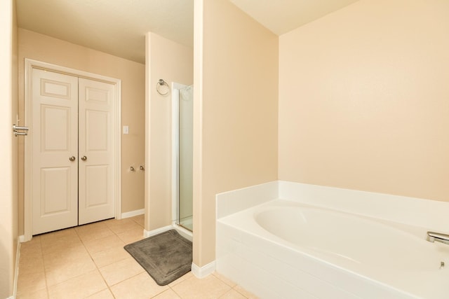 9411 Emerald Green Dr, Rosharon, TX 77583 - bathroom featuring tile patterned floors, a stall shower, a bath, and baseboards