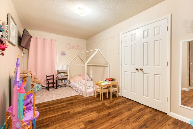 9411 Emerald Green Dr, Rosharon, TX 77583 - bedroom with baseboards, a textured ceiling, and wood finished floors