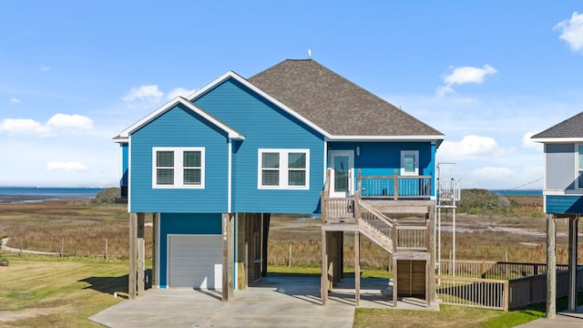 23194 Camino St, Galveston, TX 77554 - coastal inspired home with a carport, an attached garage, concrete driveway, stairs, and roof with shingles