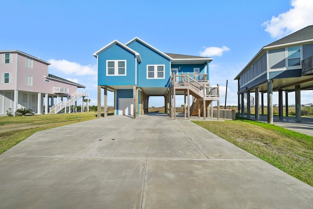 23194 Camino St, Galveston, TX 77554 - coastal home with a carport, concrete driveway, a front yard, and stairway