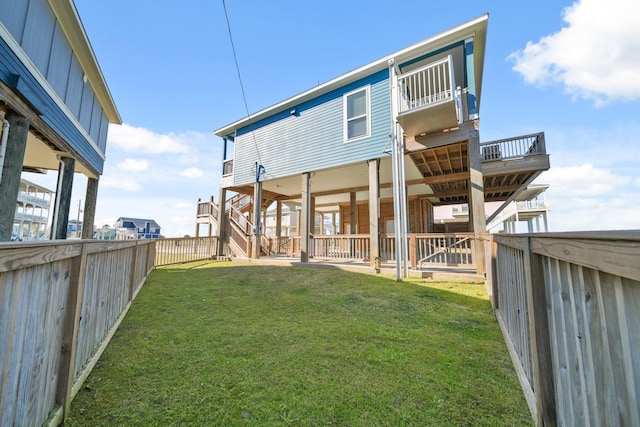 23194 Camino St, Galveston, TX 77554 - rear view of house featuring a fenced backyard, stairway, and a lawn