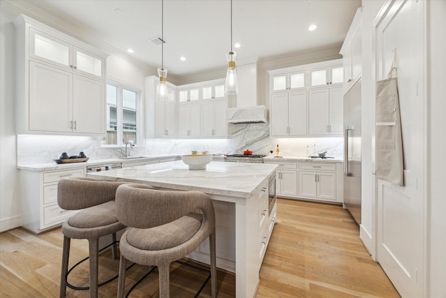 kitchen with a center island, a sink, glass insert cabinets, white cabinets, and backsplash
