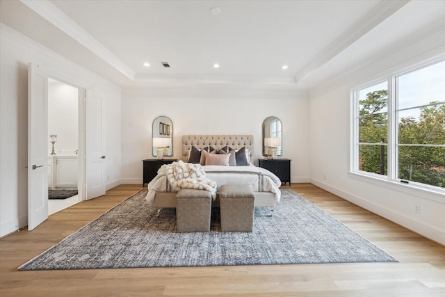 bedroom featuring a tray ceiling, visible vents, light wood finished floors, and baseboards