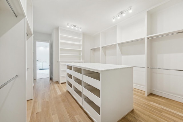 walk in closet with light wood-style floors