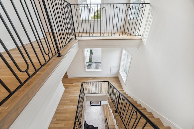stairway featuring wood finished floors, baseboards, and a high ceiling