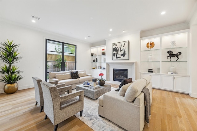living room with crown molding, a glass covered fireplace, light wood-style flooring, visible vents, and recessed lighting