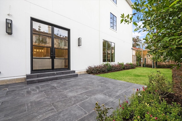 entrance to property with a yard, a patio, and stucco siding