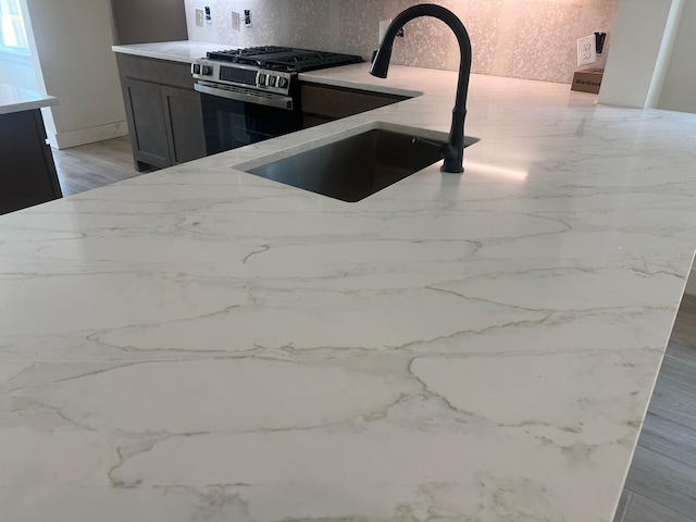 2243 Garden Arbor, Tomball, TX 77375 - kitchen featuring stainless steel range with gas cooktop, tasteful backsplash, a sink, and light stone counters