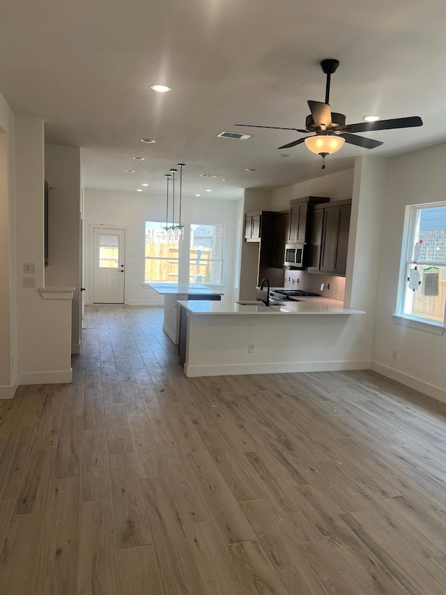 2243 Garden Arbor, Tomball, TX 77375 - kitchen with stainless steel microwave, light countertops, light wood-style floors, baseboards, and a sink