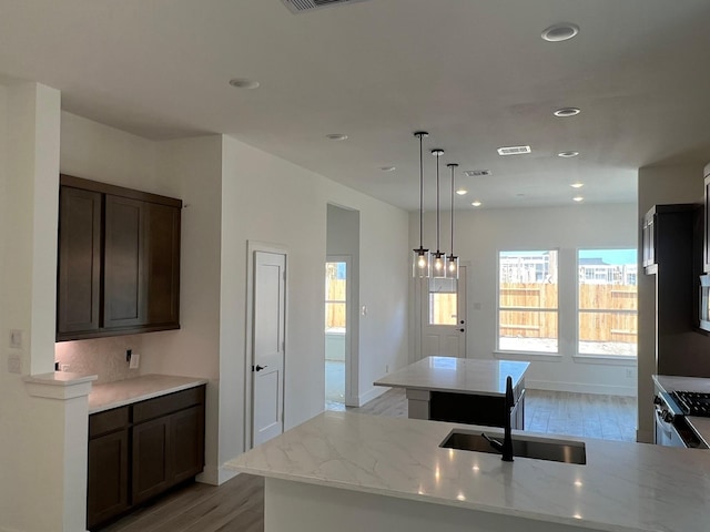 2243 Garden Arbor, Tomball, TX 77375 - kitchen with a sink, light wood finished floors, light stone counters, recessed lighting, and dark brown cabinetry