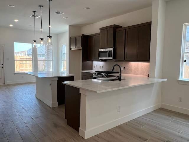 2243 Garden Arbor, Tomball, TX 77375 - kitchen featuring appliances with stainless steel finishes, light wood-type flooring, light countertops, a kitchen island, and recessed lighting