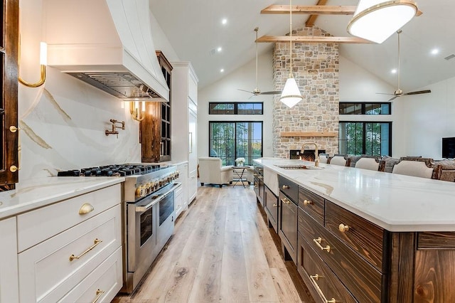 kitchen featuring range with two ovens, ceiling fan, a sink, and custom range hood