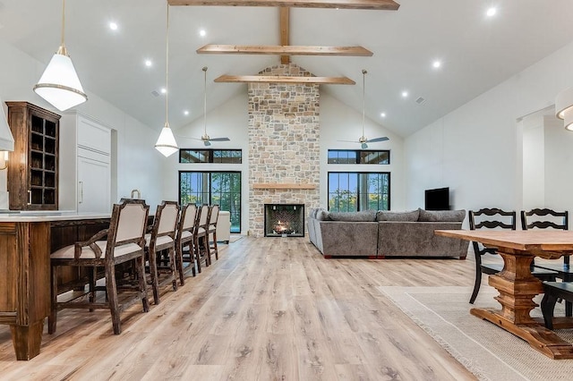 interior space with a wealth of natural light, light wood-type flooring, beamed ceiling, and a ceiling fan
