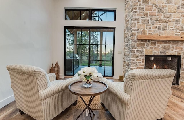 living room featuring baseboards, a stone fireplace, and wood finished floors