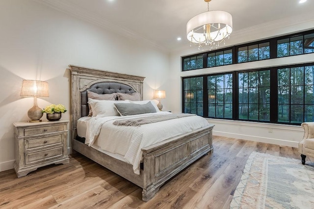 bedroom with baseboards, ornamental molding, recessed lighting, an inviting chandelier, and light wood-style floors