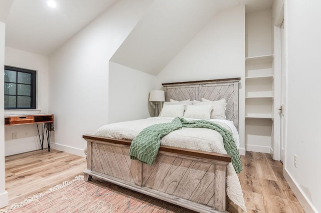 bedroom with lofted ceiling, baseboards, and light wood finished floors