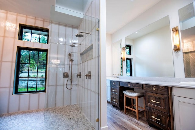 full bath with double vanity, wood finished floors, a sink, and a walk in shower