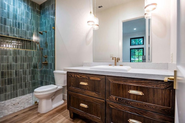 bathroom with visible vents, toilet, a walk in shower, wood finished floors, and vanity