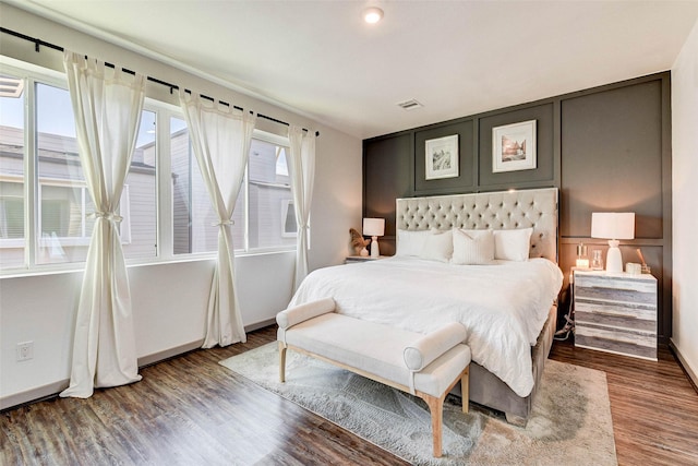 bedroom with visible vents, multiple windows, and wood finished floors