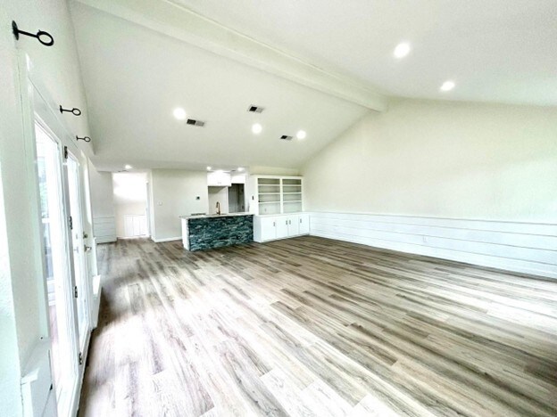 15207 Jamaica Dr, Willis, TX 77318 - unfurnished living room with vaulted ceiling with beams, wood finished floors, and visible vents