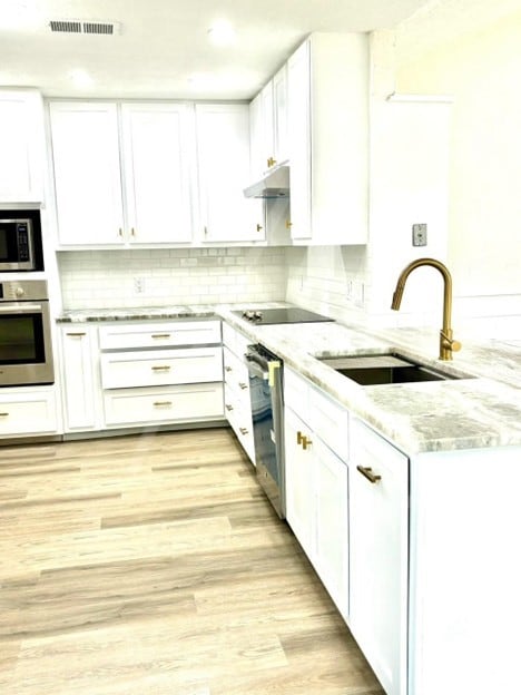 15207 Jamaica Dr, Willis, TX 77318 - kitchen featuring a sink, appliances with stainless steel finishes, white cabinets, and under cabinet range hood