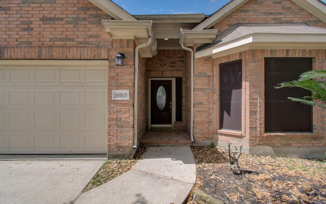 property entrance featuring an attached garage and brick siding