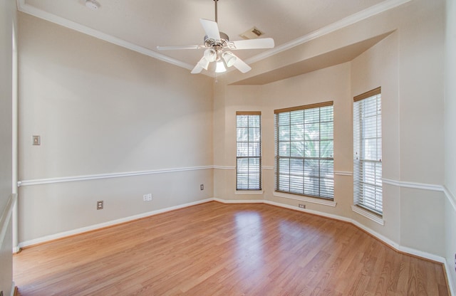 empty room with ornamental molding, baseboards, visible vents, a ceiling fan, and wood finished floors