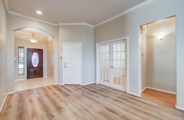foyer entrance featuring arched walkways, crown molding, baseboards, and wood finished floors