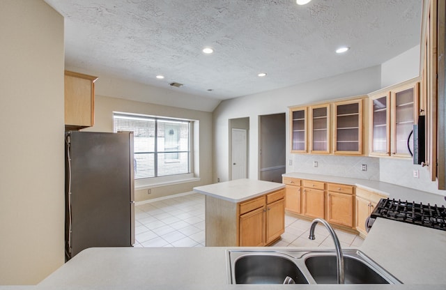 kitchen with light tile patterned flooring, a kitchen island, appliances with stainless steel finishes, a sink, and backsplash