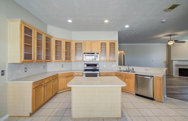 kitchen featuring a sink, a peninsula, stainless steel appliances, light tile patterned floors, and visible vents