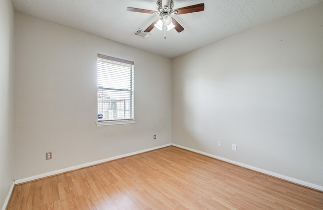 unfurnished room with a ceiling fan, wood finished floors, a textured ceiling, baseboards, and visible vents