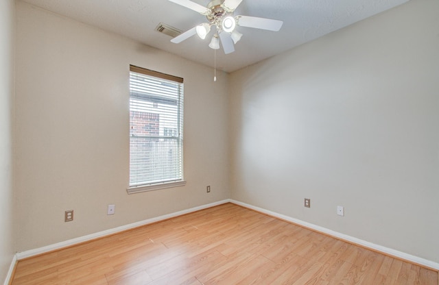 spare room with baseboards, visible vents, wood finished floors, and a ceiling fan