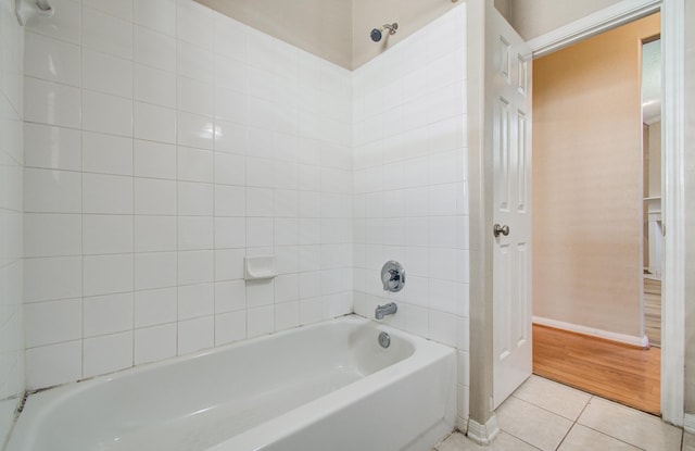 bathroom with a tub, baseboards, and tile patterned flooring