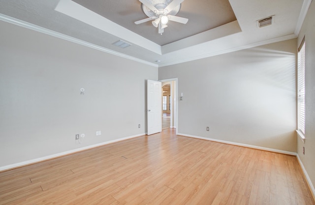 spare room with a tray ceiling, baseboards, light wood-style flooring, and a ceiling fan