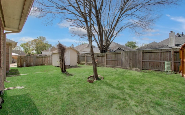 view of yard with a fenced backyard, a storage unit, and an outbuilding