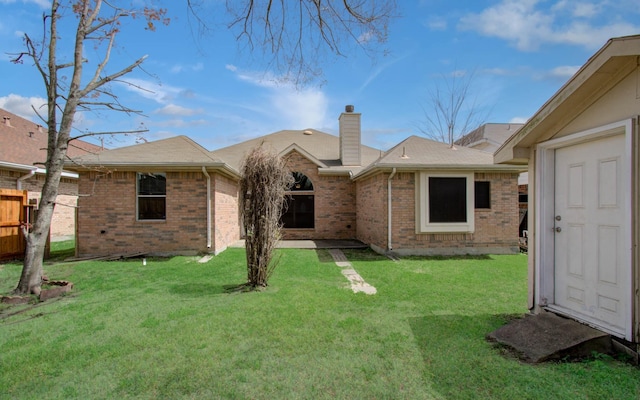 back of house featuring a chimney, brick siding, a lawn, an outdoor structure, and a shed