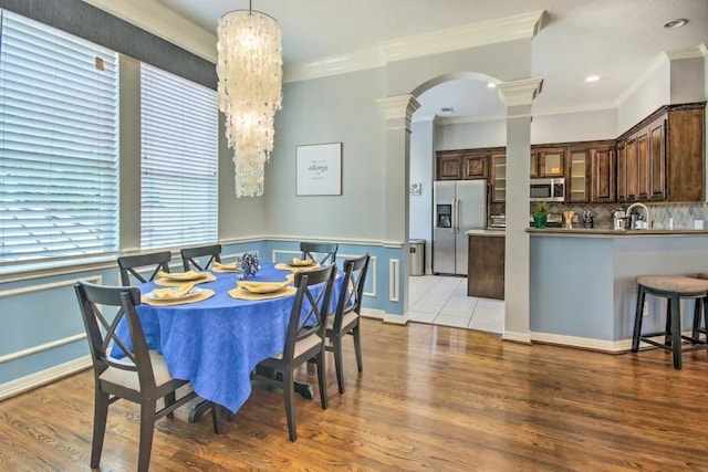 207 Knox St, Houston, TX 77007 - dining area featuring arched walkways, light wood-style floors, crown molding, and ornate columns